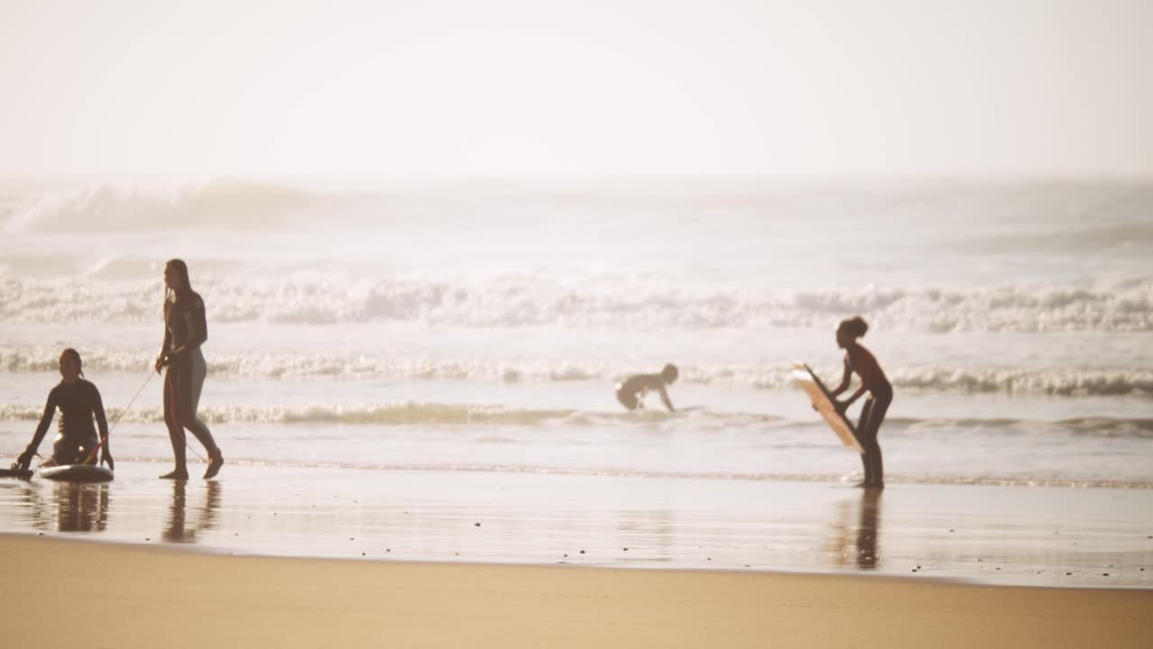 Female surfers practicing on sandy ocean coastline during golden hour time
