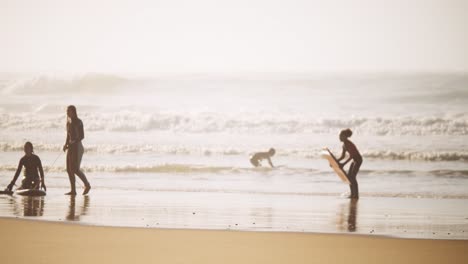 female surfers practicing on sandy ocean coastline during golden hour time