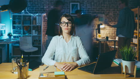woman working late at night in a office with colleagues