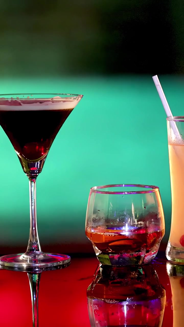 Assorted cocktails on glossy bar, vibrant lighting, hand reaches for tall drink with straw