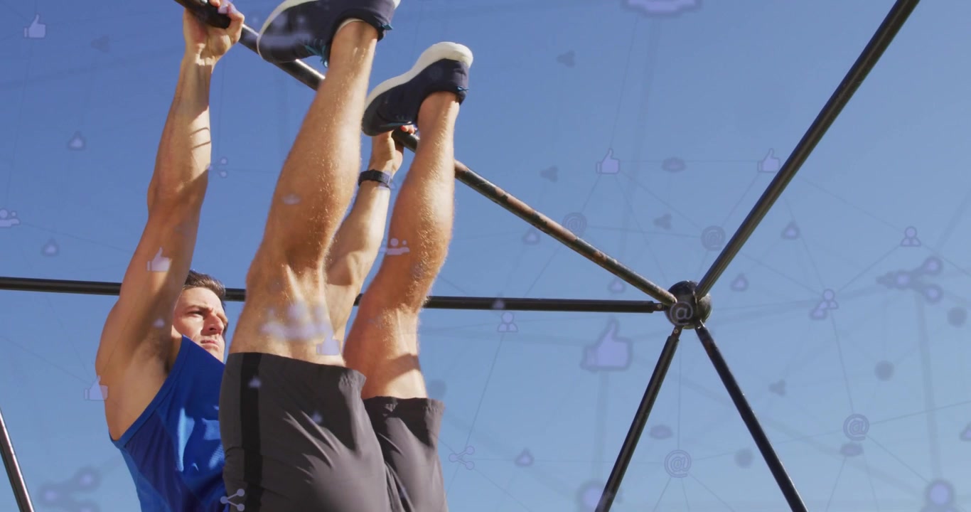 Gripping pull-up bar, man performing hanging leg raises at outdoor gym for core strength, blue top