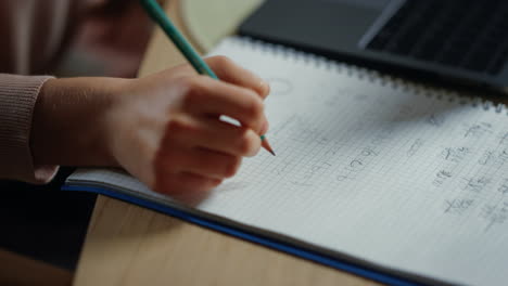 estudiante escribiendo a mano en un cuaderno en el interior. chica desconocida haciendo la tarea en el interior.