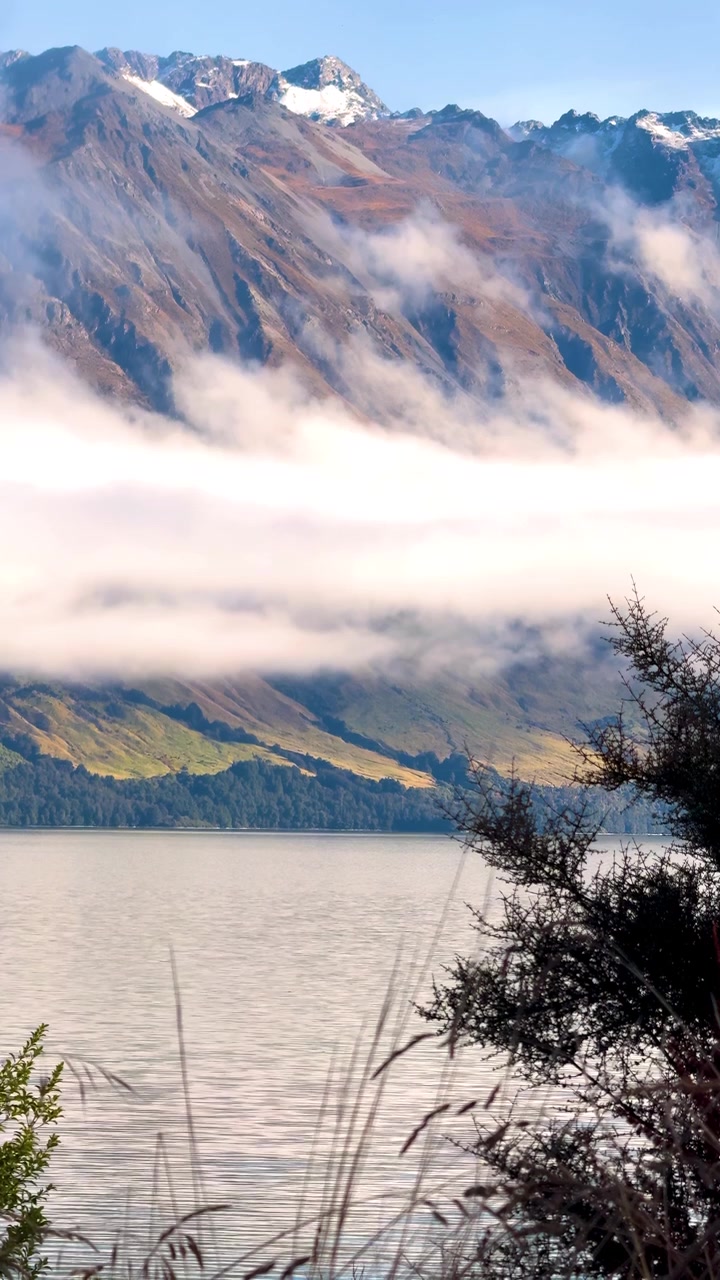 Una tranquilla scena lacustre con montagne e nuvole, catturata alla luce naturale del giorno.