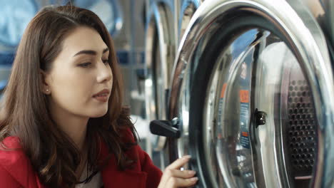 close up of pretty woman opening washing machine and taking out clean clothes after wash