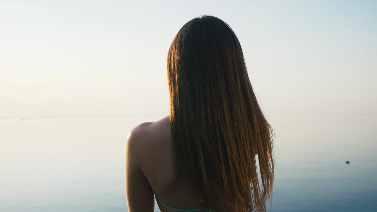 아름다운 젊은 여성이 휴가 중 해변 근처의 해가 지는 동안 스마트폰으로 사진을 찍고 있습니다.