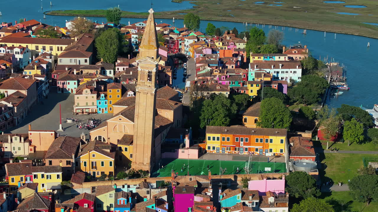 Aerial drone view of the Church of Saint Martin Bishop surrounded by colourful houses in Burano Island, Italy