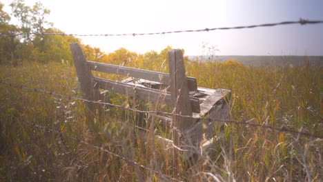 Old-wooden-bench-behind-barbed-wire-fence