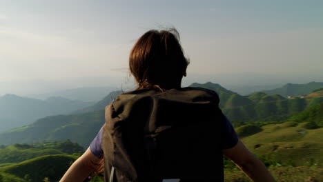 young solo asiatic female traveller backpacking in amazing mountains landscape scenario breaking fresh natural unpolluted air and sun bathing with golden hours light