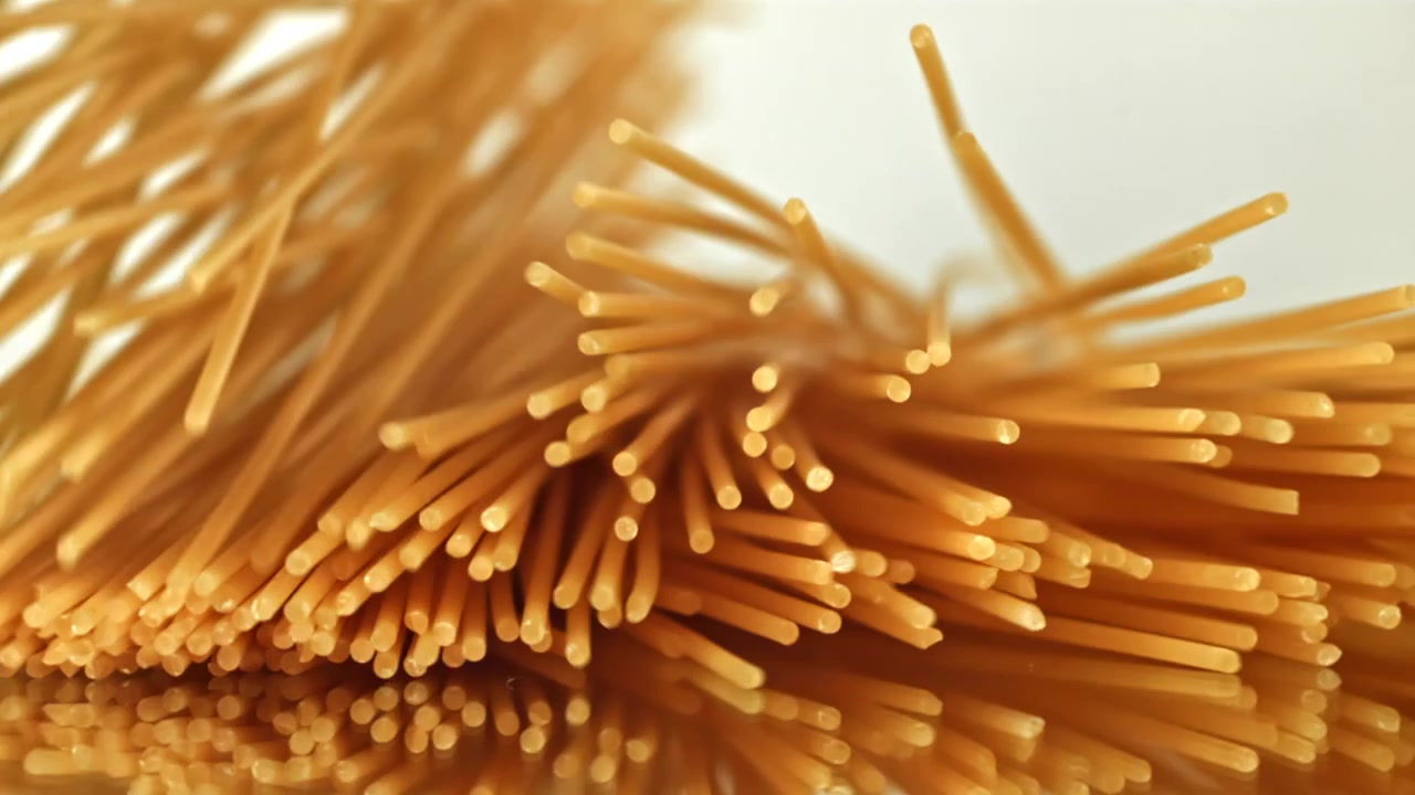 Pasta Spageti Kering Berjatuhan dalam Gerakan Lambat ke Permukaan Reflektif