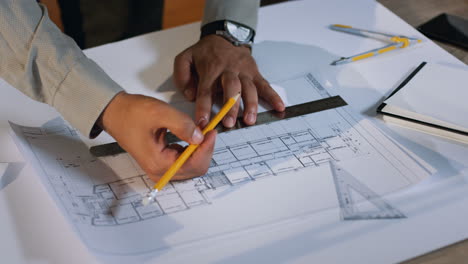 draufsicht der architektenhände, die einen bauplan auf dem großen blatt papier auf dem schreibtisch zeichnen