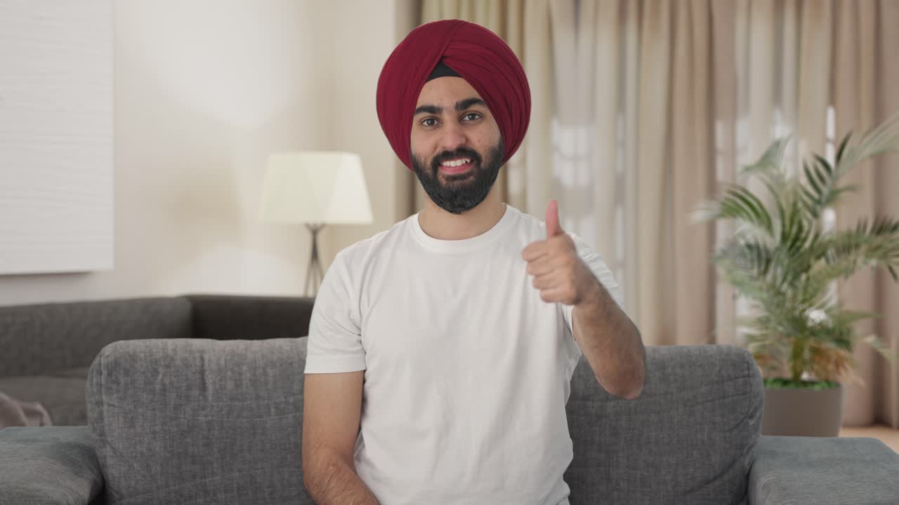 Uomo indiano Sikh felice che mostra il pollice in su