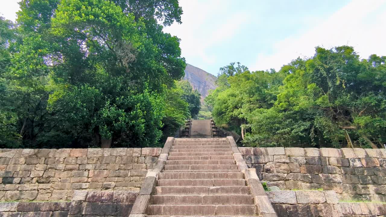 Pan up of fortified stone wall and steep stone stairway steps of Yapahuwa Rock Fortress in Sri Lanka
