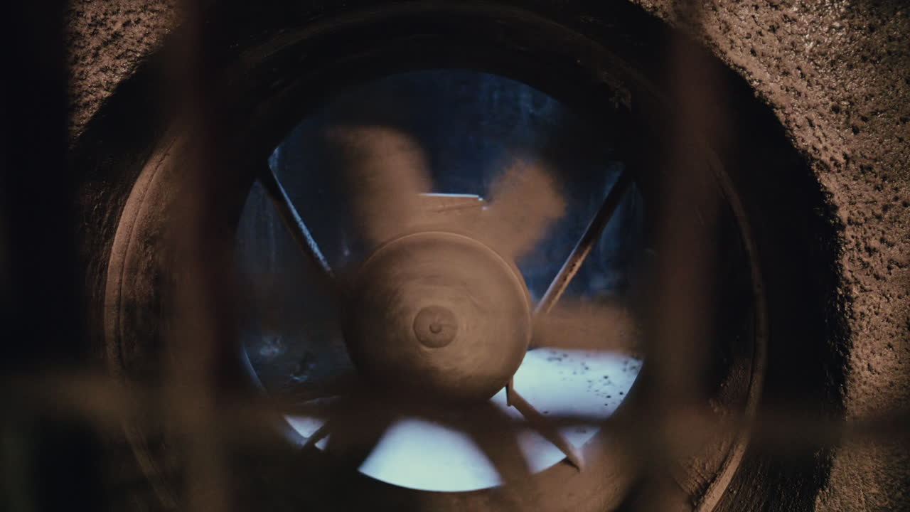 Close up of an industrial ventilation fan spinning inside a concrete structure