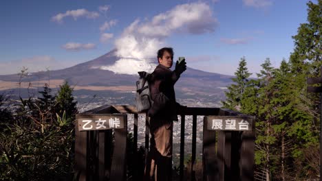 Male-hiker-taking-selfies-at-viewpoint-with-backdrop-of-Mount-Fuji