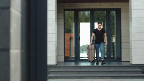 handsome coming out from luxury home man with luggage.