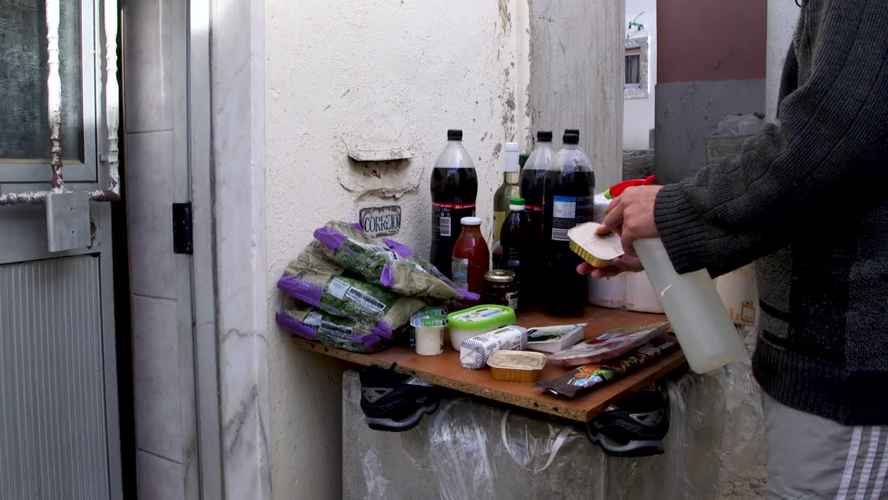 가난한 남자는 포르투갈 리스본에서 covid-19 검역 기간 동안 집에 들어가기 전에 식료품을 소독합니다.