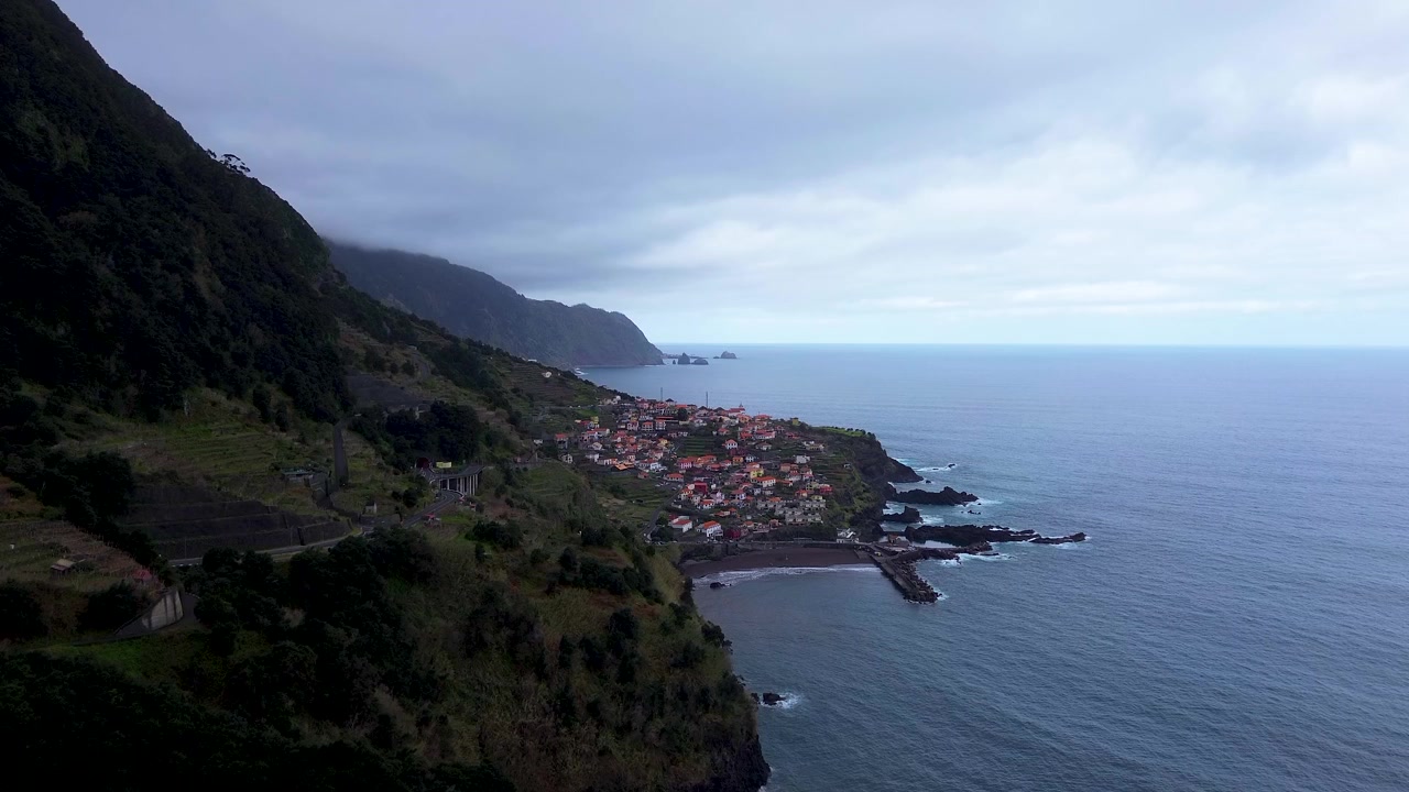 Ripresa aerea con drone di un drammatico terreno montuoso nella regione di Rabaçal sull'isola di Madeira, Portogallo, caratterizzato da ripide pareti di valle, vegetazione verde lussureggiante, cascate e aspre formazioni rocciose vulcaniche.