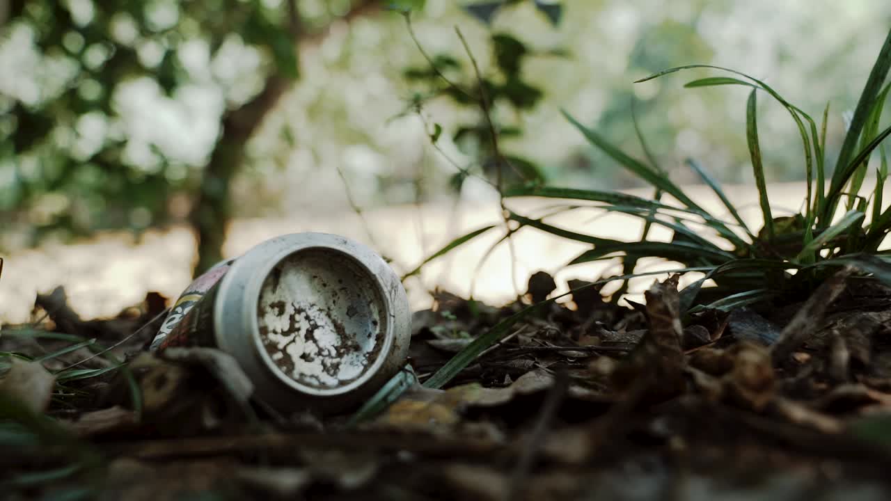 Discarded can littered on the side of a river bank is picked up and recycled.