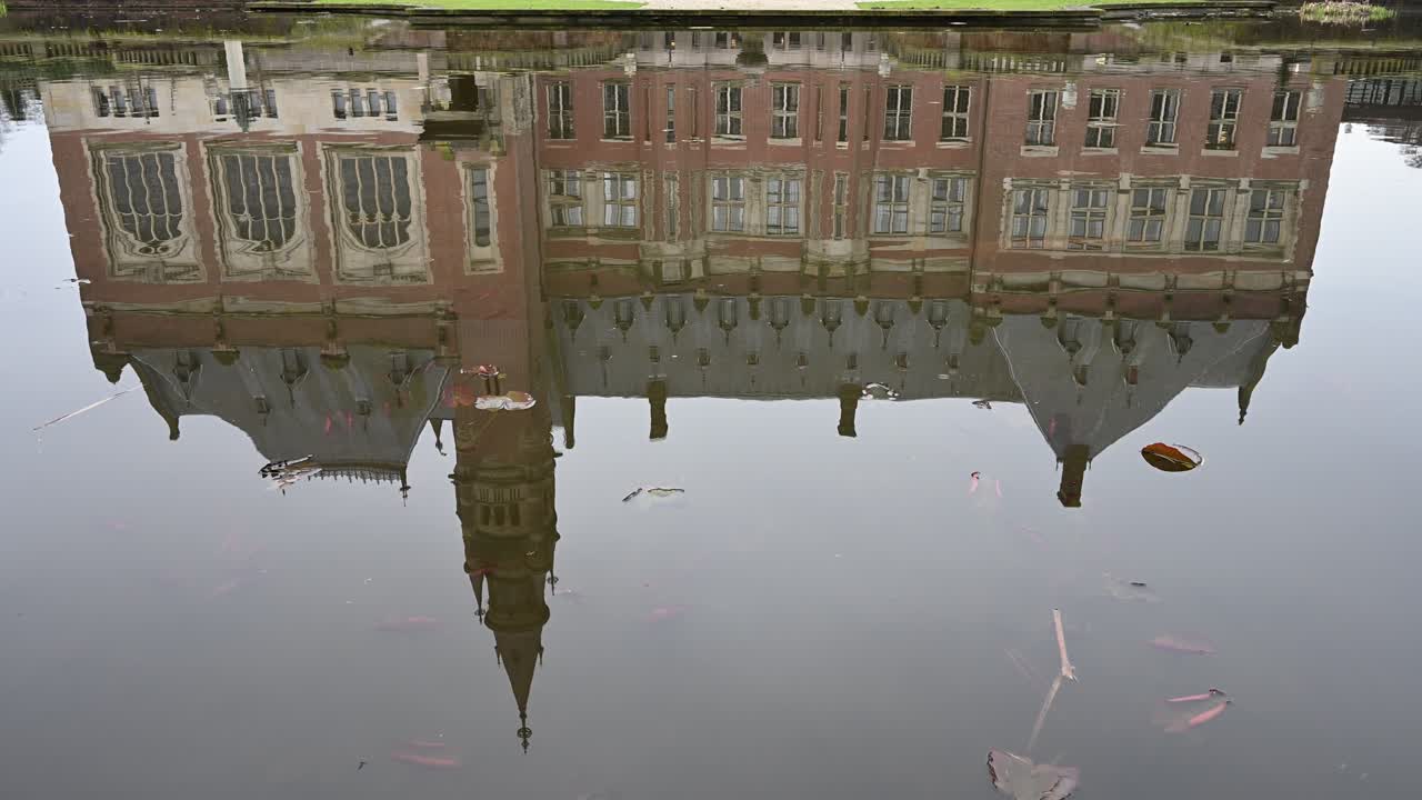 View of the Peace Palace, Vredespaleis in Dutch, reflected on the garden pond under a dull sky