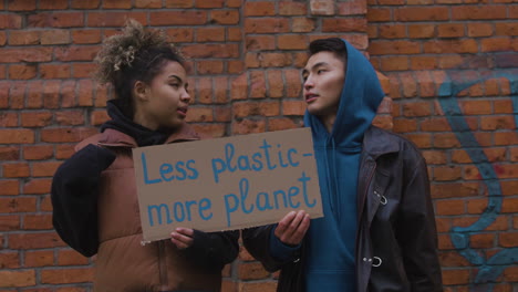 Young-Male-And-American-Female-Activists-Talking-And-Holding-A-Cardboard-Placards-During-A-Climate-Change-Protest