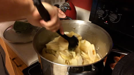 Hombre-Haciendo-Puré-De-Manzana-En-La-Estufa-De-La-Cocina