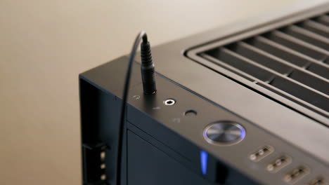 el hombre enchufa y luego desenchufa el cable de los auriculares en el conector de la computadora de escritorio