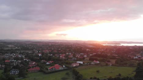 Toma-Aérea-Ascendente-Sobre-Una-Zona-Residencial-Durante-La-Puesta-De-Sol.