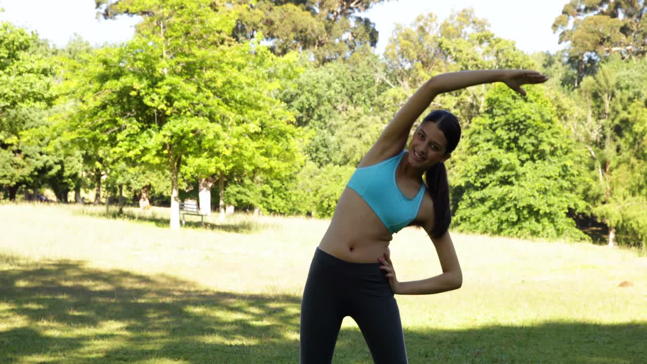 hermosa bruneta en forma estirándose en el parque
