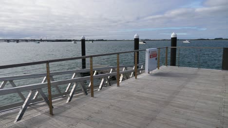 mar tranquilo con barcos y yates flotando en el agua desde el paseo marítimo de madera cerca de la playa en tauranga, región de la bahía de la abundancia en la isla norte, nueva zelanda