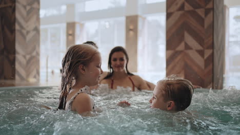 un niño y una niña están jugando en la piscina. la familia está descansando en el jacuzzi de un centro de spa moderno.