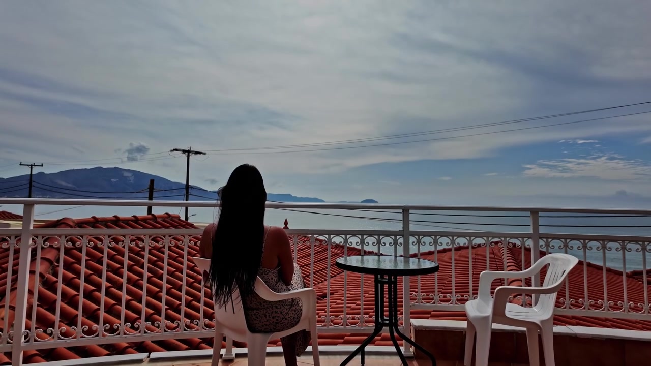 Donna che si gode la splendida vista mare da un balcone ad Atene, Grecia