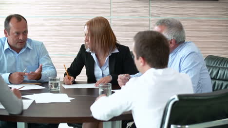 Businessmen-And-Businesswomen-Sitting-At-A-Table-While-Talking-In-A-Meeting