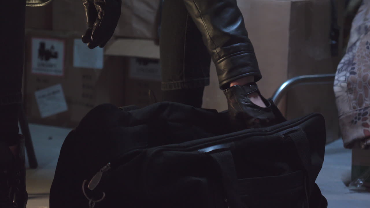 검은 가죽 장갑을 끼고 더플백에서 드라이버와 펜치를 검사하는 범죄자