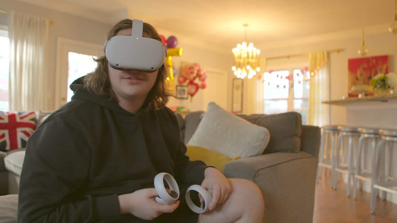 Un ragazzo adolescente a casa che indossa un visore di realtà virtuale e tiene in mano dei controller si immerge in un mondo simulato