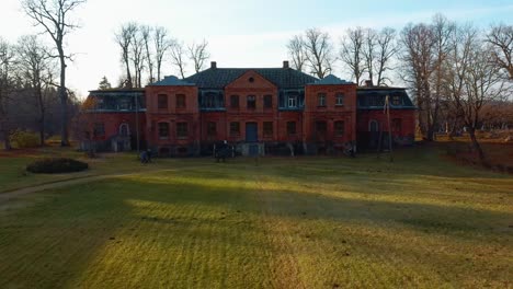 old red brick house, katvari manor in latvia and katvaru lake in the background