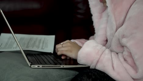 person wearing pink bathrobe scrolling on touchpad on laptop