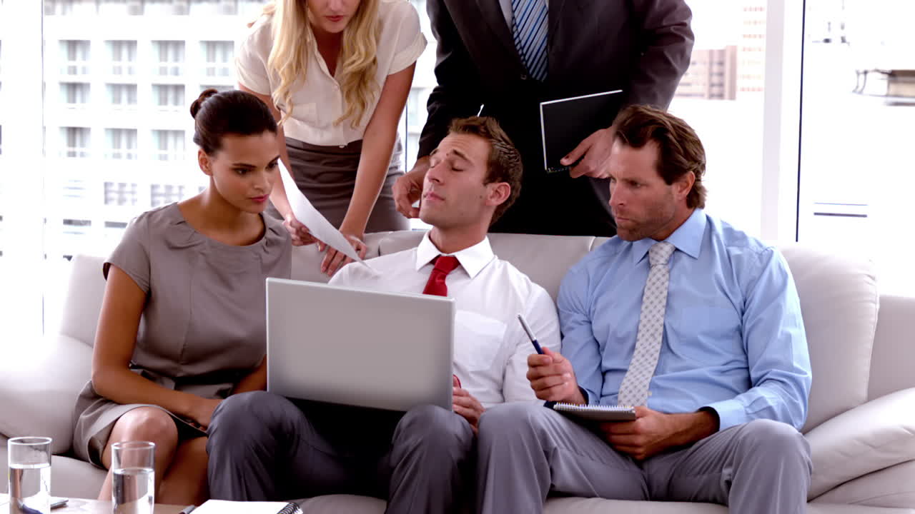 Equipo de negocios reuniéndose en el sofá con portátil