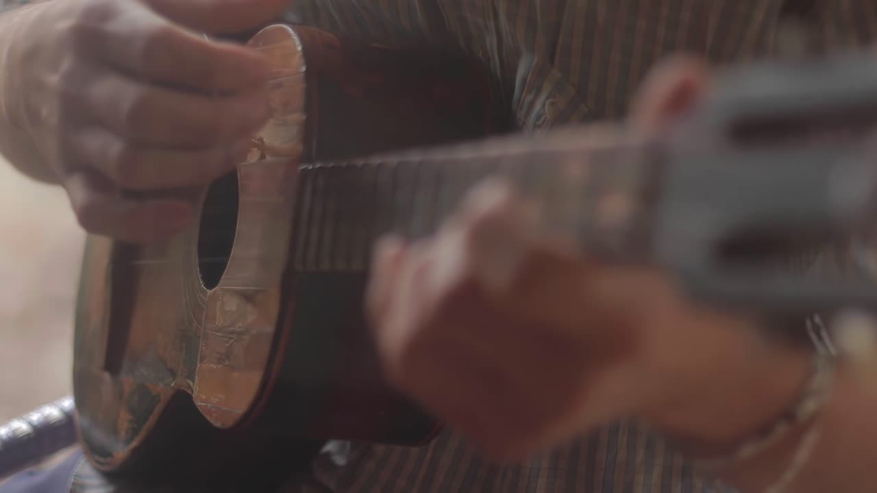 4K detail shot of a person playing an instrument called Venezuelan Cuatro, with a selective focus and blurred background