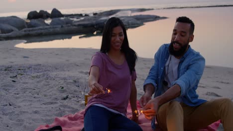 Happy-young-mixed-race-couple-having-fun-with-sparklers-at-beach-4k