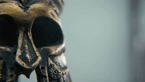 A-close-up-macro-creative-shot-of-a-Spartan-design,-two-different-ancient-warrior-metal-bronze-helmets,-glowing-textured-face-mask-shapes,-studio-lighting,-4K-cinematic-video,-Slow-Motion,-pan-left