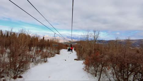 beautiful point of view from a ski lift at a ski resort in colorado on an overcast winter day with tall aspen and pine trees with stunning desert orange and red colored landscape in the background