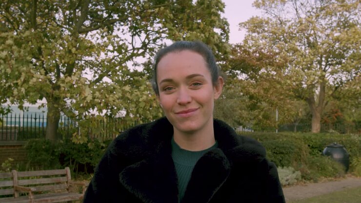 Donna che sorride alla telecamera di giorno in un parco.