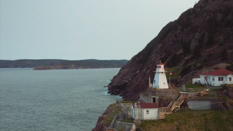 rugged cliffs line the shore and bright white fort amherst lighthouse at edge of land