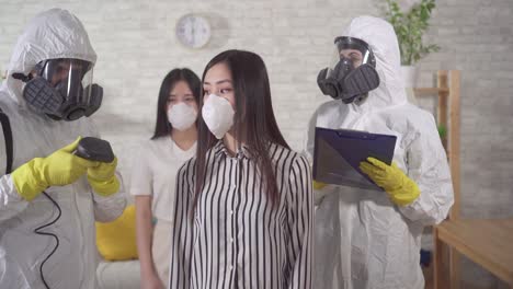 doctors in protective uniform measure the temperature of asian person at home