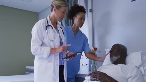 diverse female doctor talking to male patient in hospital bed