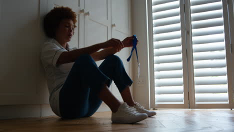 unhappy and demotivated nurse wearing uniform sitting on floor at home after long shift