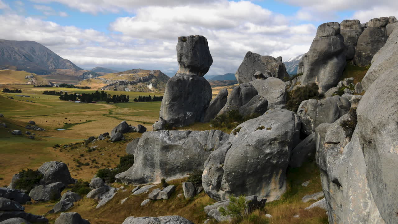 toma panorámica cinematográfica que muestra la formación de rocas en la colina del castillo y el hermoso paisaje rural en segundo plano durante el día nublado con el cielo azul