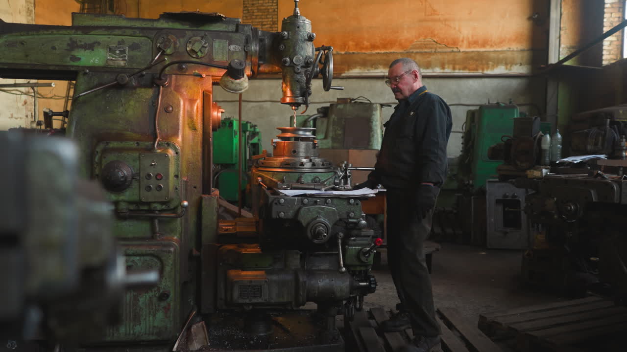 старший работник с усами контролирует работу буровой машины