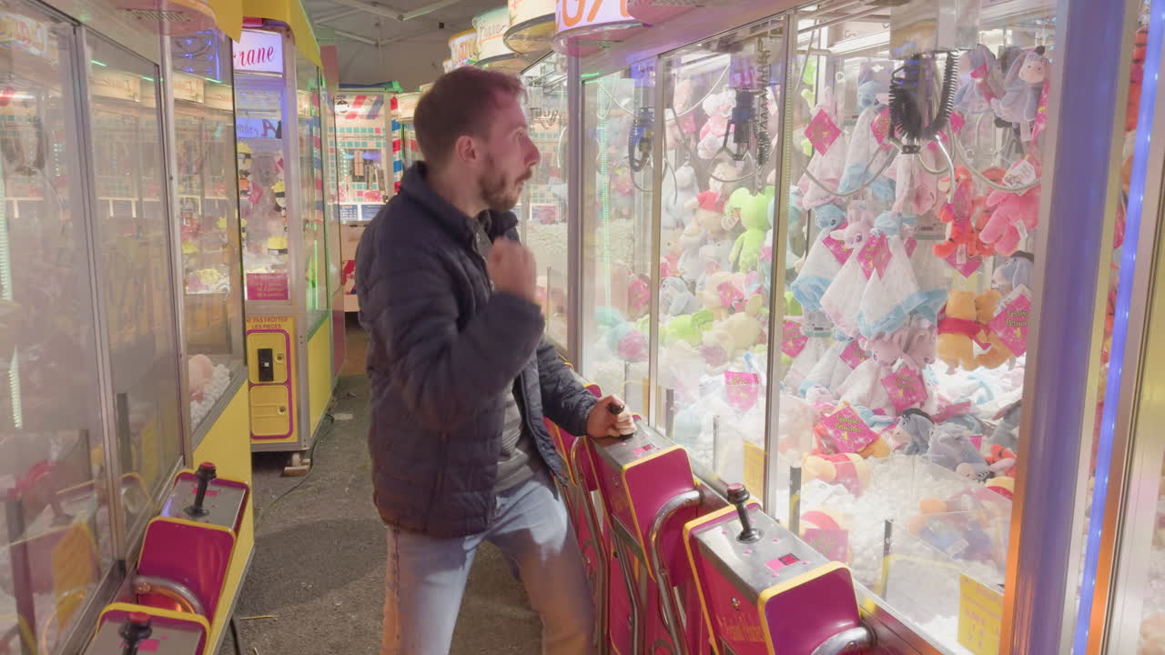 Man playing claw machine at a lively fair at night in Montrichard Val de Cher