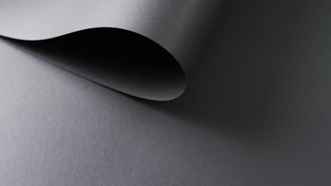 Close-up-of-roll-of-black-paper-and-copy-space-on-black-background